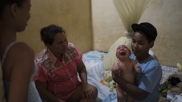 Solange Ferreira, left, watches as her nephew Jhonnata tries to calm Jose Wesley.