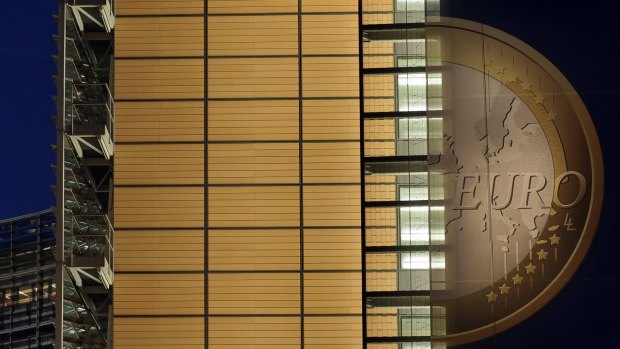 A giant banner, featuring the euro and promoting stronger European economic governance, is illuminated at the headquarters of the EU Berlaymont Building in Brussels.