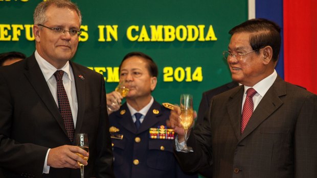 Australia's then immigration minister, Scott Morrison, and Cambodian Interior Minister Sar Kheng hold flutes of champagne after signing a deal to resettle refugees in Cambodia  on September 26, 2014, in Phnom Penh.