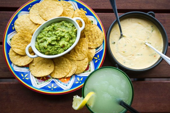 Con queso and guacamole dips with corn chips.