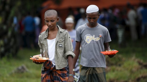 Rohingya migrants collect their breakfast from a kitchen tent at a temporary shelter in Aceh Timur in Indonesia's Aceh province.