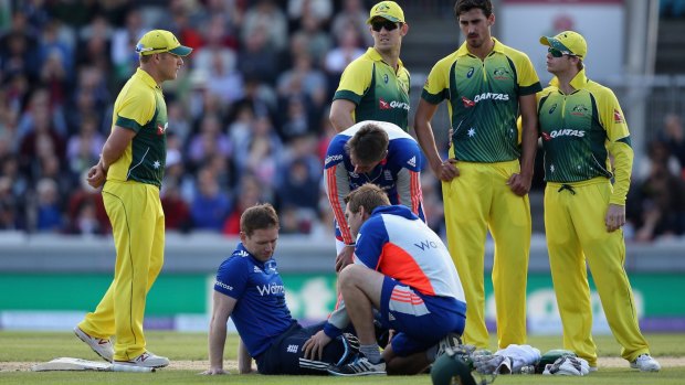 Eoin Morgan of England receives treatment after being struck on the head by a short ball from Mitchell Starc.