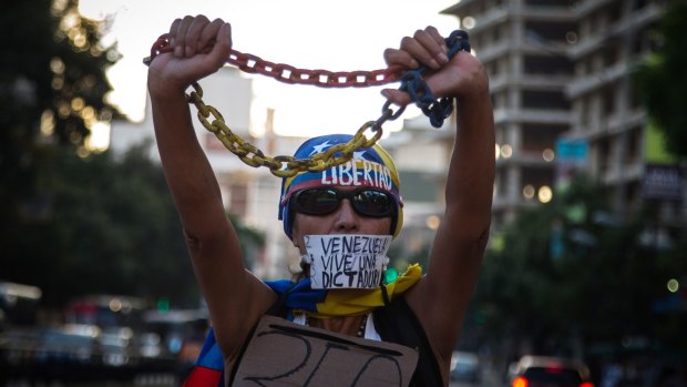 A woman protests against a Supreme Court decision to seize the powers of the opposition-led Congress. Her mouth sticker reads: "Venezuela lives in a dictatorship."