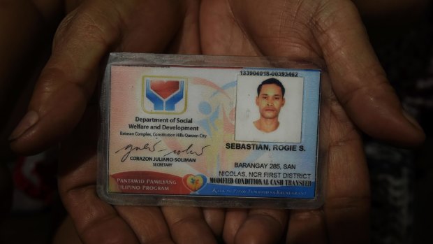 A relative of Rogie Sebastian holds his ID card. 