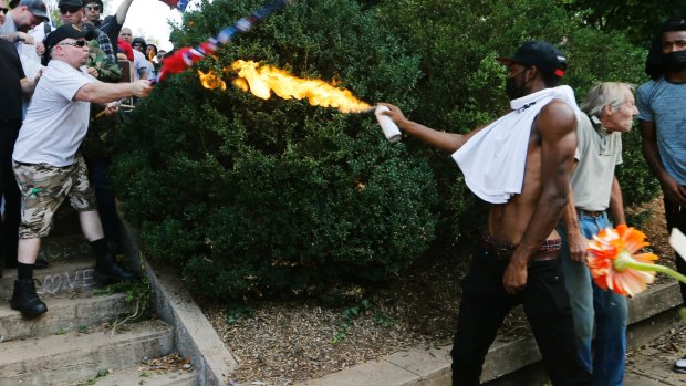 A counter-demonstrator uses a lighted spray can against a white nationalist demonstrator.