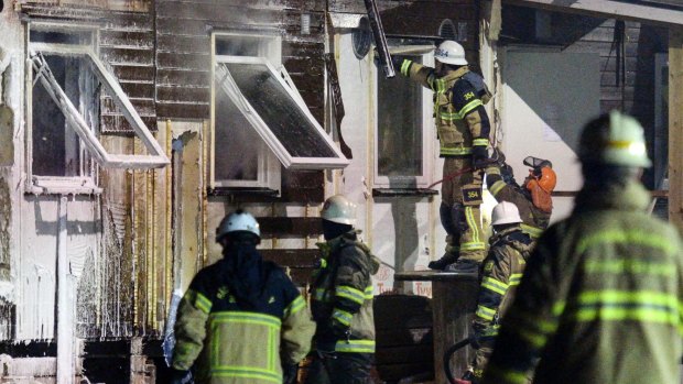 Firefighters extinguish a fire after evacuating residents from the refugee accommodation in Fagersjo, south of Stockholm, Sweden. 
