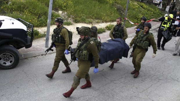 Israeli soldiers carry the body of one of two Palestinians killed after a stabbing attack in Hebron on Thursday. 