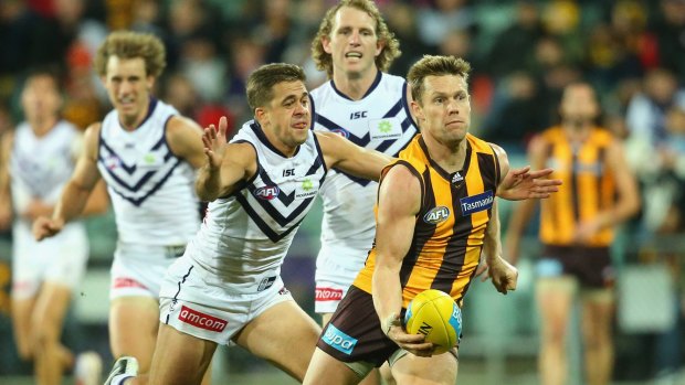 Sam Mitchell gets a handball away  with Stephen Hill of the Dockers in pursuit.