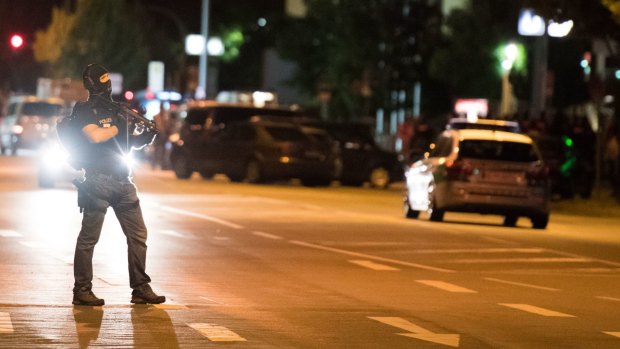 A masked policeman stands on the street in front of the Olympia mall where a shooting took place in Munich.