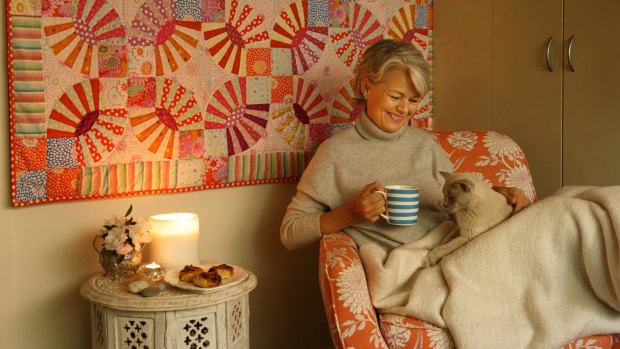 Danish-Australian Charlotte Thaarup is a proponent of the Danish concept of Hygge. Here she demonstrates the concept with a comfortable chair, blanket, candles, Danish pastries, tea, a book, and her cat Millie.