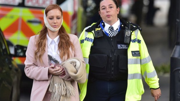 An injured woman is assisted by a police officer close to Parsons Green station.