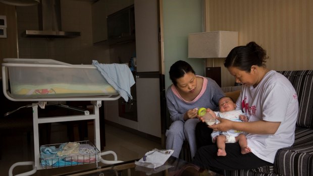 Dong Guangjie, a postpartum nanny (or yuesao), feeds Li Rui’s baby son.