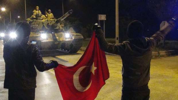 Cheering Turks wave toward tanks heading toward the Syrian border, in Hatay, Turkey.