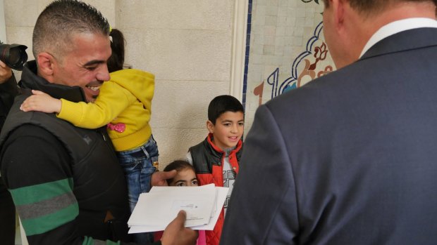 Peter Dutton hands a visa to refugee family member Marwan Alkhdah