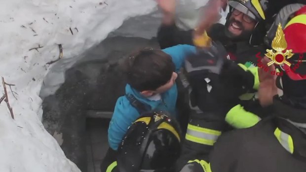 Italian firefighters extract a child from under snow and debris at Rigopiano.