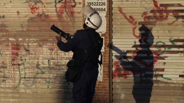 A riot policeman fires tear-gas towards anti-government protesters in Daih, Bahrain.