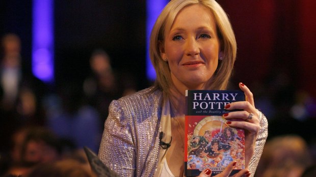 J.K. Rowling poses with a copy of Harry Potter and the Deathly Hallows.