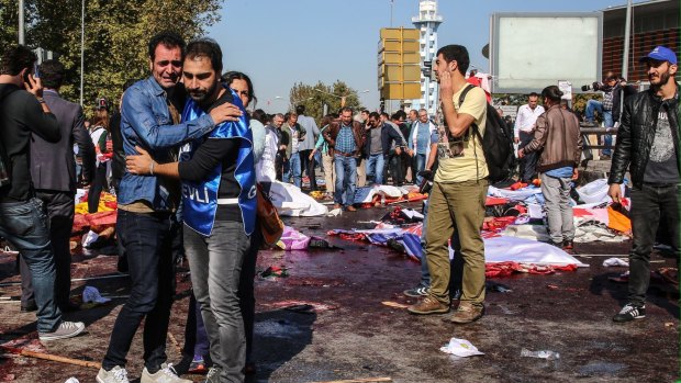 Survivors stand among the dead and injured at the blast scene after an explosion during a peace march in Ankara on October 10.