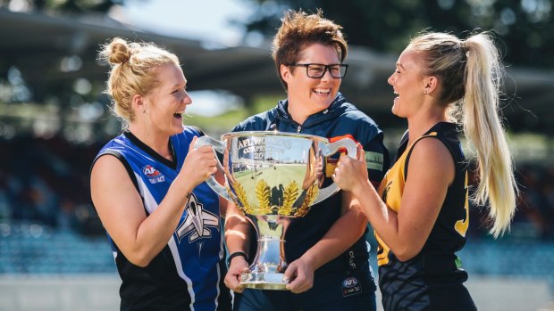 Women's ACT AFL players Britt Tully and Ella Ross with Adelaide coach Bec Goddard and the 2017 premiership cup.