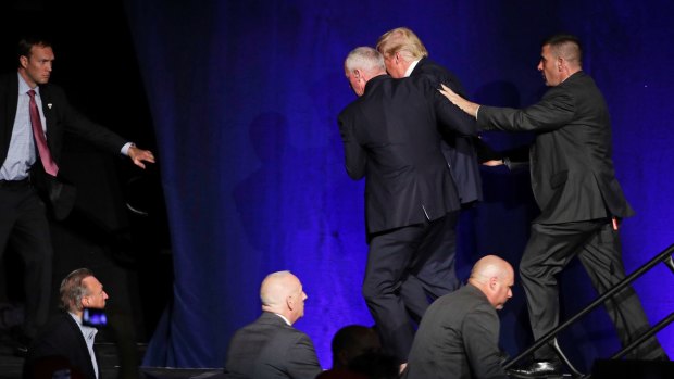 Members of the Secret Service rush Republican presidential candidate Donald Trump off the stage at a campaign rally in Reno, Nevada.