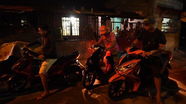 Police on motorbikes leave the scene where three men were slain in a drug related killing in Caloocan, Manila, Philippines, in September. 