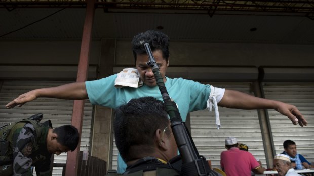 A resident who escaped from the inner city is frisked by local police as part of their security processing in Marawi City, Philippines.