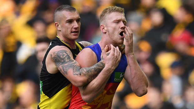 Brisbane's Nick Robertson clutches his face after an incident involving Richmond's Dustin Martin.