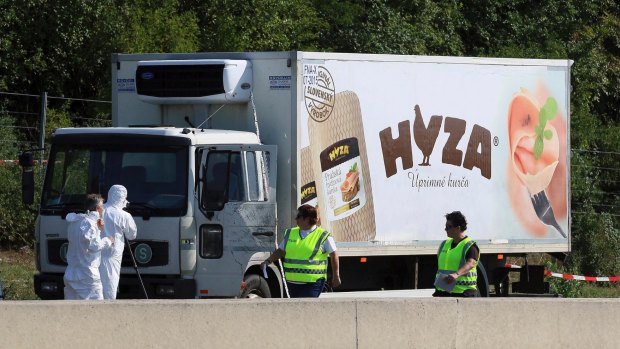Investigators stand near an abandoned truck on a highway near Parndorf, Austria, where 71 badly decomposed bodies of migrant men, women and children, were discovered in August 2015.