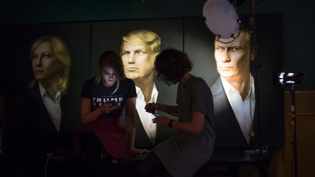 Two women wait in front of portraits of French Front National leader Marine Le Pen, US President-elect Donald Trump and Russian President Vladimir Putin, for a live telecast of election results in a pub in Moscow.