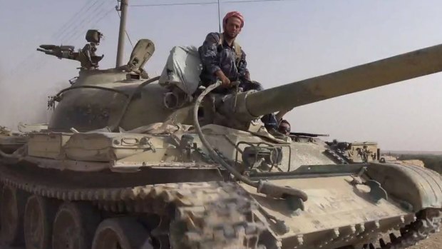 Common enemy: An Islamic State militant sits on a tank captured from Syrian government forces.