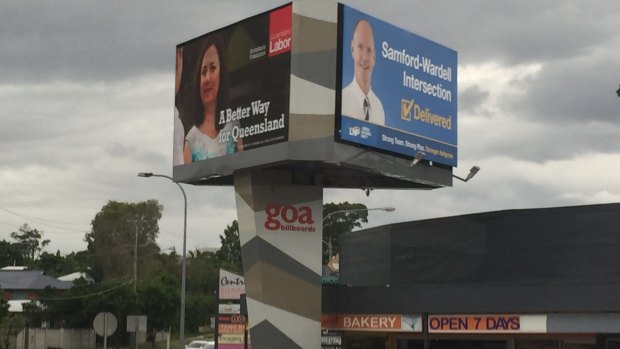 Annastacia Palaszczuk and Campbell Newman hold competing signs at the Samford Road-Wardell Street intersection in the seat of Ashgrove.