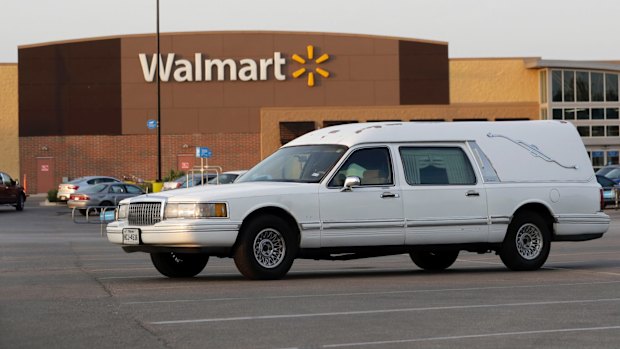 A hearse sits in the parking lot of a Walmart store where eight people were found dead.