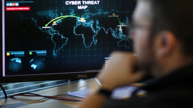 Threat track: An information analyst works in front of a map tracking cyber threats.
