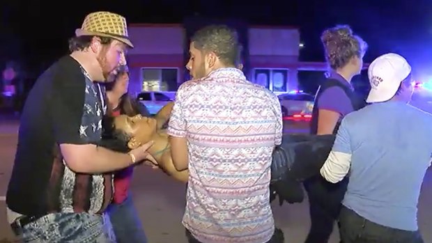 An injured person is escorted out of the Pulse nightclub in Orlando after being shot.