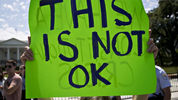 A demonstrator holds a sign that reads "This is not OK" during a protest outside the White House in Washington, DC.