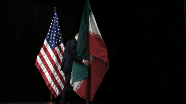 A staff member removes the Iranian flag from the stage after a group picture with foreign ministers and representatives of Unites States, Iran, China, Russia, Britain, Germany, France and the European Union during the Iran nuclear talks at the Vienna International Center in Vienna, Austria Tuesday July 14, 2015.  After 18 days of intense and often fractious negotiation, world powers and Iran struck a landmark deal Tuesday to curb Iran's nuclear program in exchange for billions of dollars in relief from international sanctions ? an agreement designed to avert the threat of a nuclear-armed Iran and another U.S. military intervention in the Muslim world. (Carlos Barria, Pool Photo via AP)