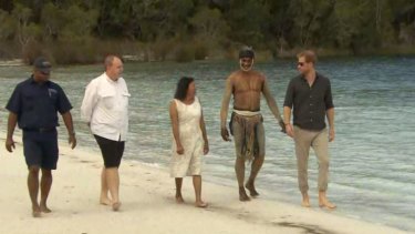 Prince Harry takes a stroll on the shore of Lake McKenzie with representatives of the Butchulla people.