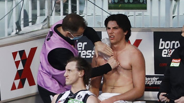 Oliver Henry of the Magpies is seen on the bench with a shoulder injury.