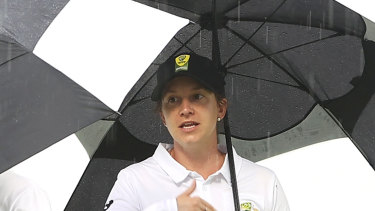 Umpires stand under umbrellas on a wet day in Canberra. 