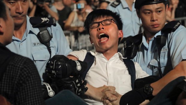 Pro-democracy activist Joshua Wong is detained by police officers after climbing the Golden Bauhinia in Hong Kong on Wednesday.
