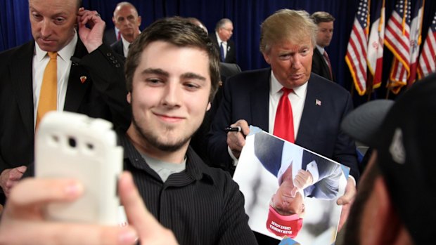 Nathan Lanferman, 17, of Newton, attempts to take a picture of Republican presidential candidate Donald Trump following a rally at Des Moines Area Community College in Iowa.