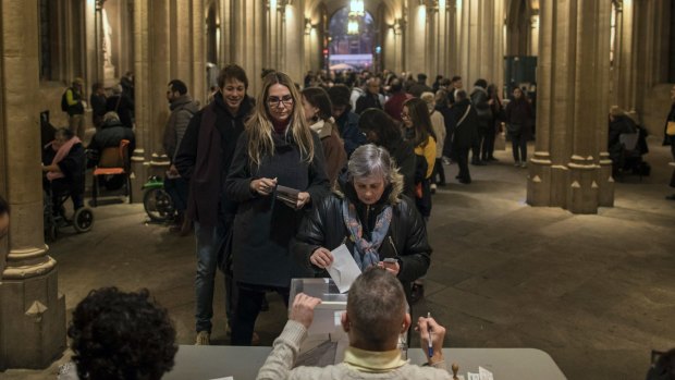 A woman casts her ballot for the Catalan regional elections at a polling station in Barcelona, Spain. 