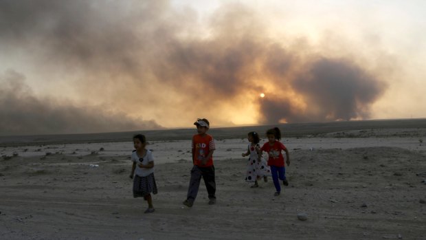 Smoke rises as children flee during clashes between Iraqi security forces and IS members.