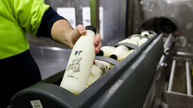 Bottles of raw milk are packed into baskets before being sent through a cold-press machine.