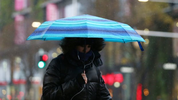 A woman takes cover during rainy weather on Thursday in Sydney.