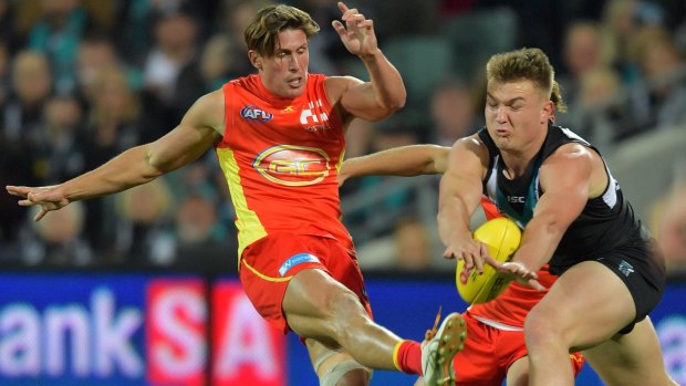 Off the boot: Gold Coast's David Swallow get spoiled by Power's Ollie Wines.