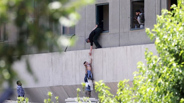 A child is lowered from a window in the Iranian Parliament building following the attack.