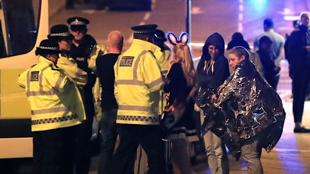 Emergency services personnel speak to people outside Manchester Arena after an explosion.