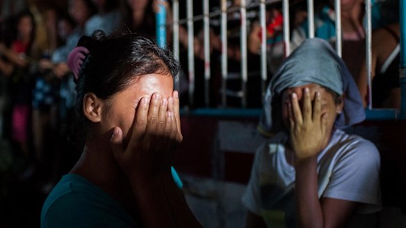 Two women await the fate of their loved ones during an alleged police drug raid on a suspected drug den in Manila. 