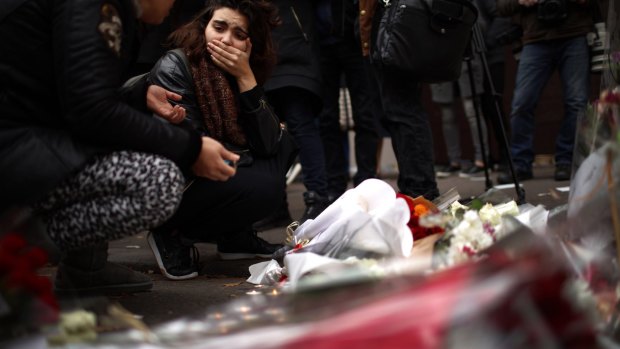 A woman reacts after places flowers near the  Bataclan Concert Hall.